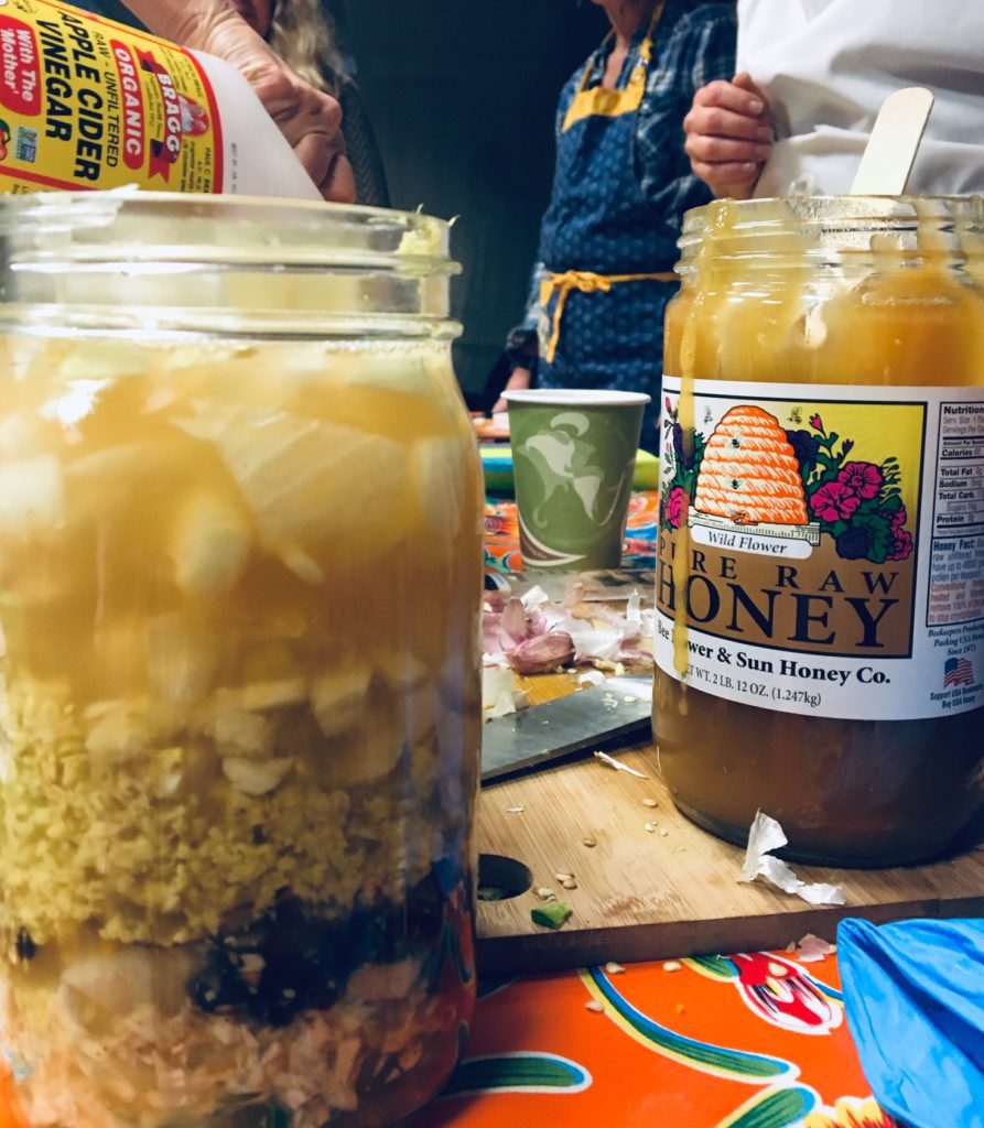 A jar of cereal and honey is next to an orange.